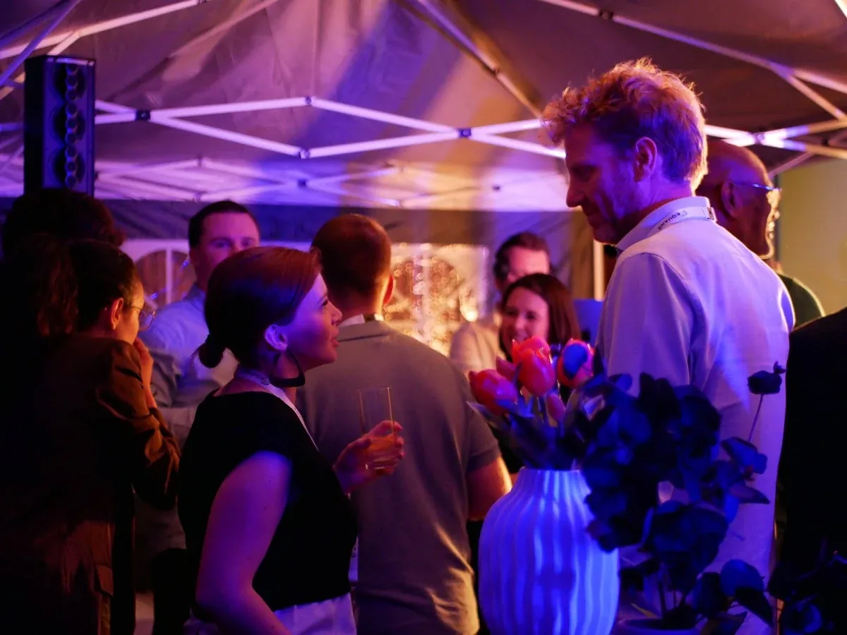 Invités en pleine discussion sous une tente éclairée en violet, lors de la soirée clients d'Equans France