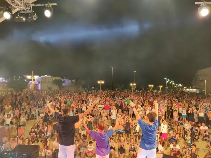 Concert en plein air filmé depuis la scène, le public bras levés