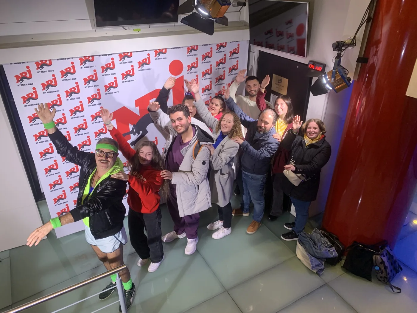 Public réuni devant le décor NRJ et l'enseigne ON AIR pendant l'enregistrement d'une émission